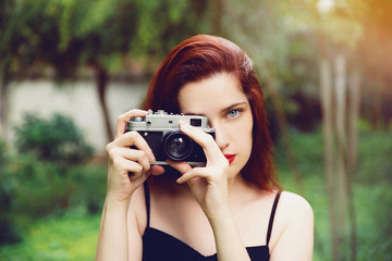 Young beautiful woman taking photos with retro camera