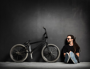Obraz na płótnie Canvas Young smiling man sitting next to his BMX bike.