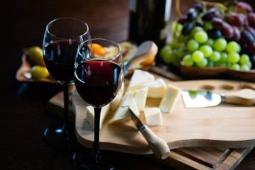 Pouring red wine into the glass in the background composition of appetizers