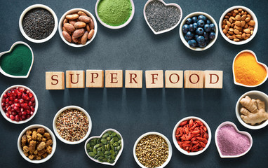 Various colorful superfoods in bowls on dark background