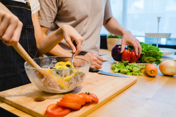 Asian woman prepare salad food in the kitchen. Beautiful happy asian couple are cooking in the kitchen. Young asian couple have romantic time while staying at home. Couple lifestyle at home concept.