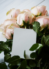 Flat lay stylish mockup photo with a blank greeting card and roses bouquet flowers. Feminine photo for blog and website.