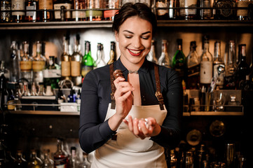 Smiling bartender girl breaking an ice cube