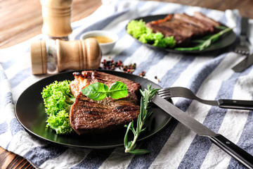 Plate with tasty steak and herbs on table