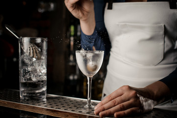 Bartender girl throwing into the transparent cocktail one olive