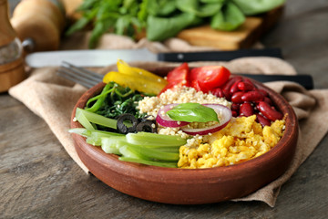 Plate with tasty quinoa salad on wooden table