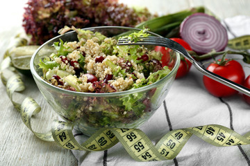 Bowl with tasty quinoa salad and measuring tape on wooden table. Diet concept