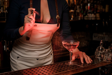 Bartender girl spraying on the delicious cocktail in the bar