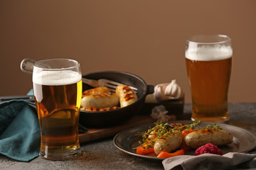 Glasses of delicious beer with grilled sausages on grunge table