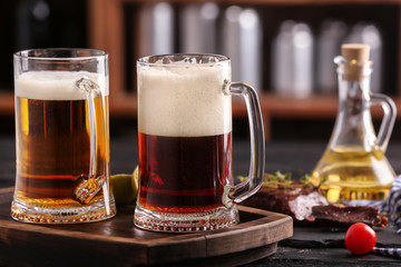 Mugs of delicious beer on wooden table