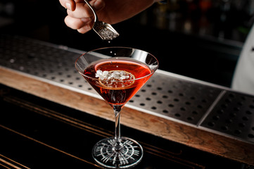 Girl decorated fresh red cocktail with dried orange with little silver beads