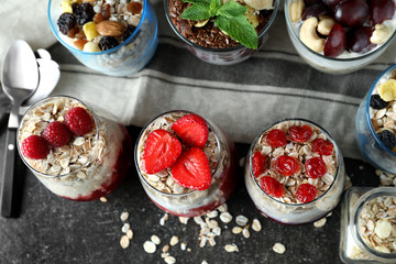Assortment of tasty oatmeal desserts with fresh berries and nuts in glasses on table