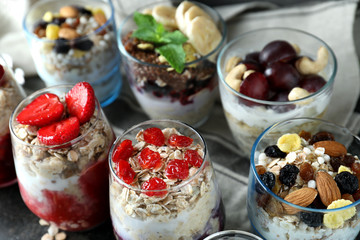 Assortment of tasty oatmeal desserts with fresh berries and nuts in glasses on table