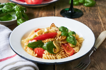 Pasta with tomatoes, zucchini and basil in a bowl