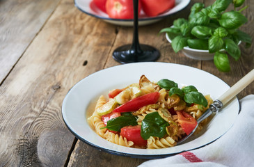 Pasta with tomatoes, zucchini and basil in a bowl