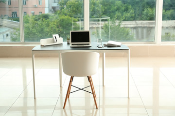 Stylish workplace with laptop on table in office
