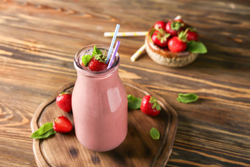 Bottle with tasty strawberry smoothie on wooden table