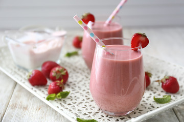 Glass with tasty strawberry smoothie on wooden table