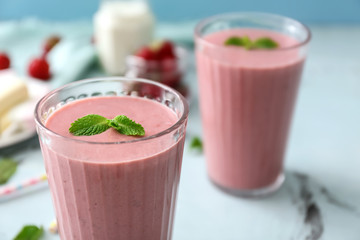 Glass with tasty strawberry smoothie on table, closeup