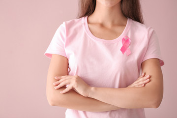 Beautiful woman with pink ribbon on color background. Breast cancer concept