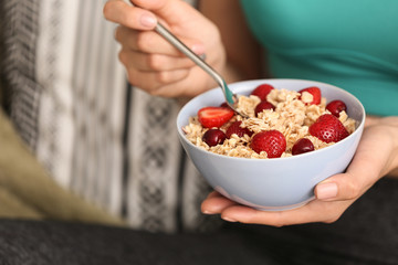 Young woman eating tasty oatmeal at home, closeup