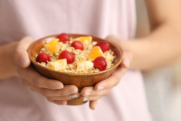 Young woman with bowl of tasty oatmeal, closeup
