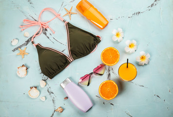 Composition with swimsuit, sunscreen cream and juice on color background