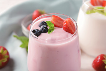 Glass with yogurt and berries on table, closeup