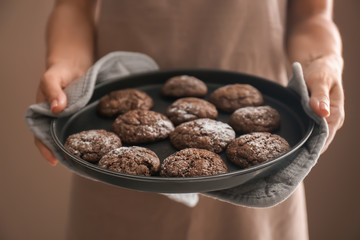 Woman holding baking tray with chocolate cookies, closeup