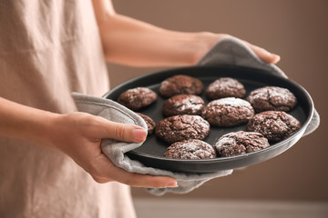 Woman holding baking tray with chocolate cookies, closeup