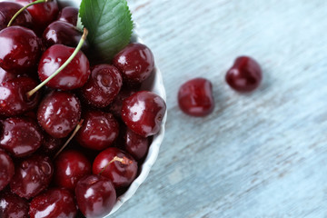Bowl with tasty ripe cherries on wooden background, closeup