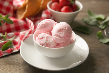 Bowl with tasty strawberry ice cream on wooden table