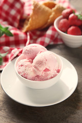 Bowl with tasty strawberry ice cream on wooden table
