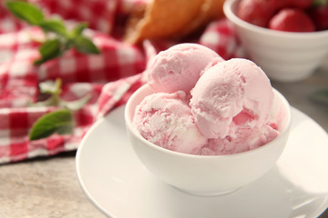 Bowl with tasty strawberry ice cream on wooden table