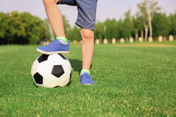 Cute little boy with soccer ball in park on sunny day