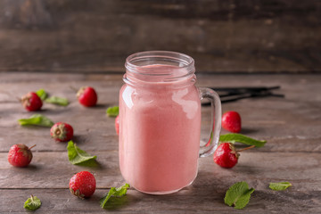 Mason jar with strawberry smoothie on wooden table