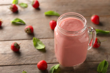 Mason jar with strawberry smoothie on wooden table