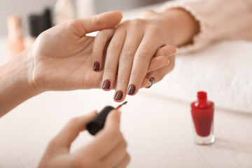 Young woman getting professional manicure in beauty salon