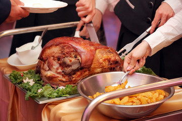 waiter serves roasted meat and baked potatoes at the party or wedding reception