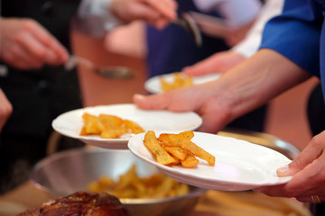 waiter serves roasted meat and baked potatoes at the party or wedding reception