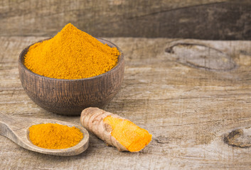 Turmeric powder and fresh turmeric on wooden background - Curcuma longa