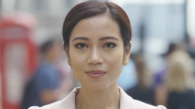 Portrait of young asian female looking and smiling to camera, in slow motion