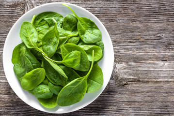 Fresh spinach. Green vegetable leaves on plate, healthy food, vegan diet concept.