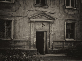Fototapeta na wymiar Entrance to a very old house. Old residential building. Kazakhstan (Ust-Kamenogorsk). Old architecture. Architectural heritage. Black and white photo. Vintage style. Grunge architecture