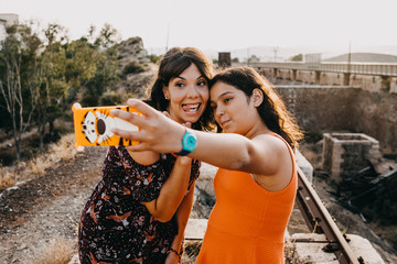 .Two young sisters enjoying a fun summer afternoon on abandoned train tracks, taking fun pictures together. Family vacation. Lifestyle.