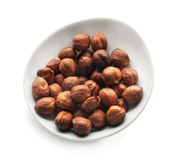 Bowl with tasty hazelnuts on white background