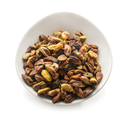 Bowl with tasty pistachio nuts on white background
