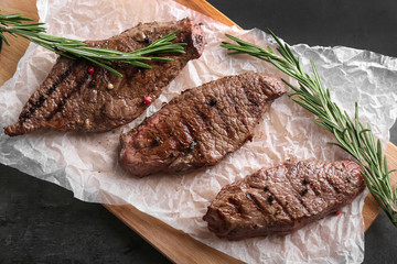 Tasty grilled meat with rosemary on wooden board