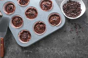Baking tin with tasty chocolate muffins on table