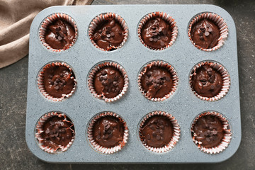 Baking tin with tasty chocolate muffins on table